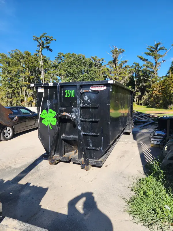 Irish Greens container 2510 on a work site with lumber stacked nearby